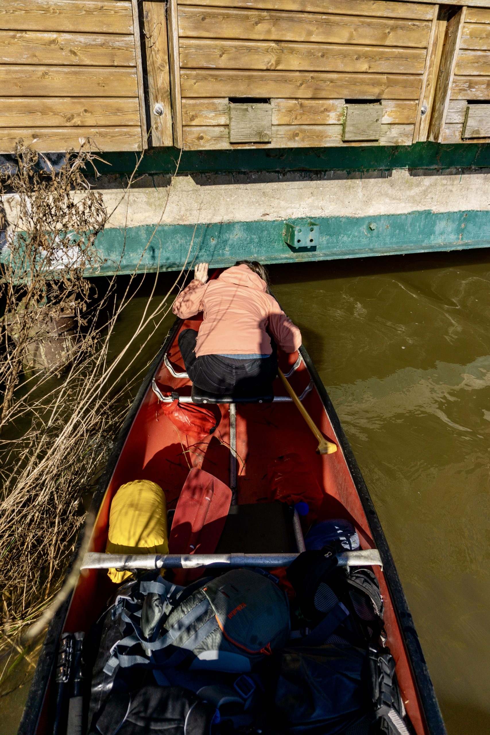 Frau im Kanu quetscht sich unter einer Brücke hindurch